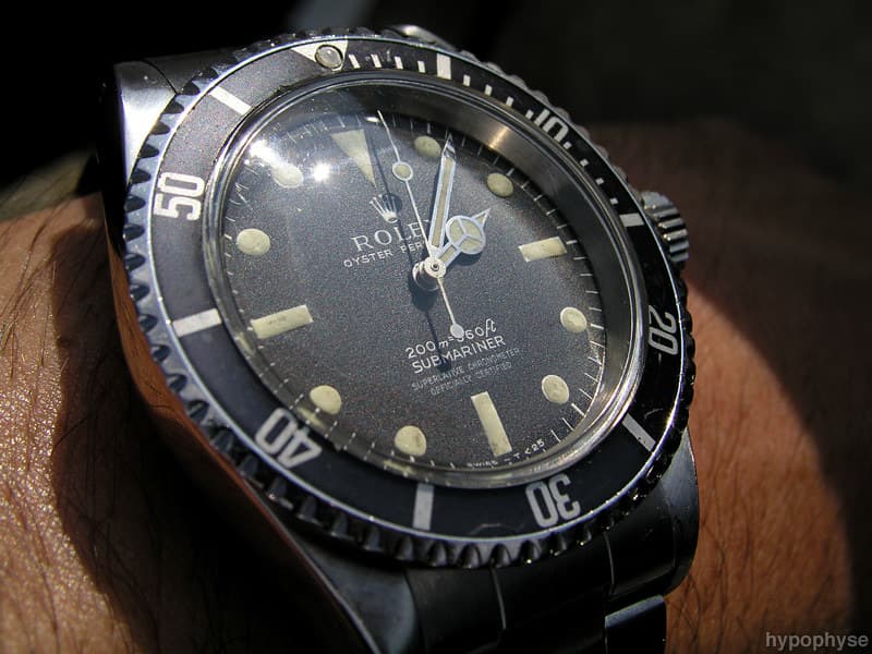 Close wrist shot of the same 5512 with aged lume plots; meters-first depth rating and four-line chronometer text are legible. · Photo: hypo.physe (Flickr) · CC BY-SA 2.0 · https://creativecommons.org/licenses/by-sa/2.0/ · Source: https://www.flickr.com/photos/hypophyse/3956993576/