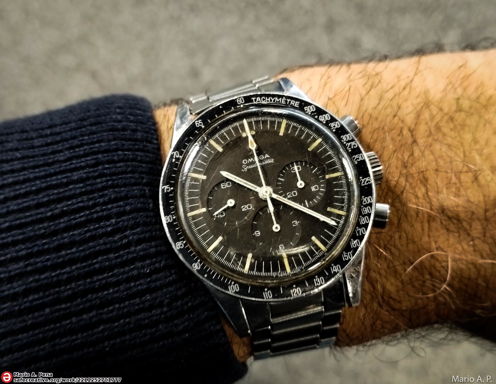 Omega Speedmaster 105.003 (owner's title “Ed White 1965”) on the wrist: black dial without “Professional”, baton hands, straight lugs, no crown guards, black tachymetre bezel. · Photo: Mario A. P. · CC BY-SA 2.0 · https://creativecommons.org/licenses/by-sa/2.0/ · Source: https://www.flickr.com/photos/oneras/52522494739/